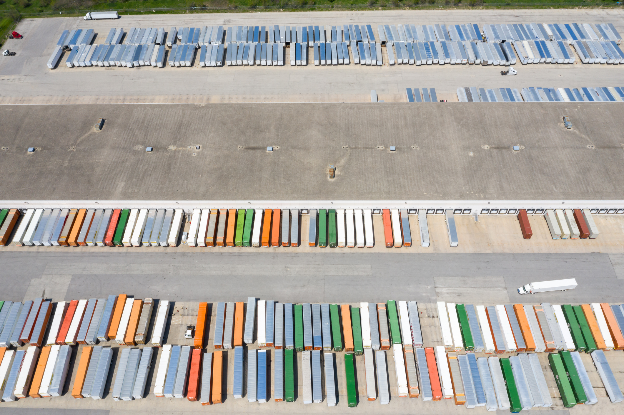 Aerial of million square foot high bay distribution warehouse with containers and truck traffic